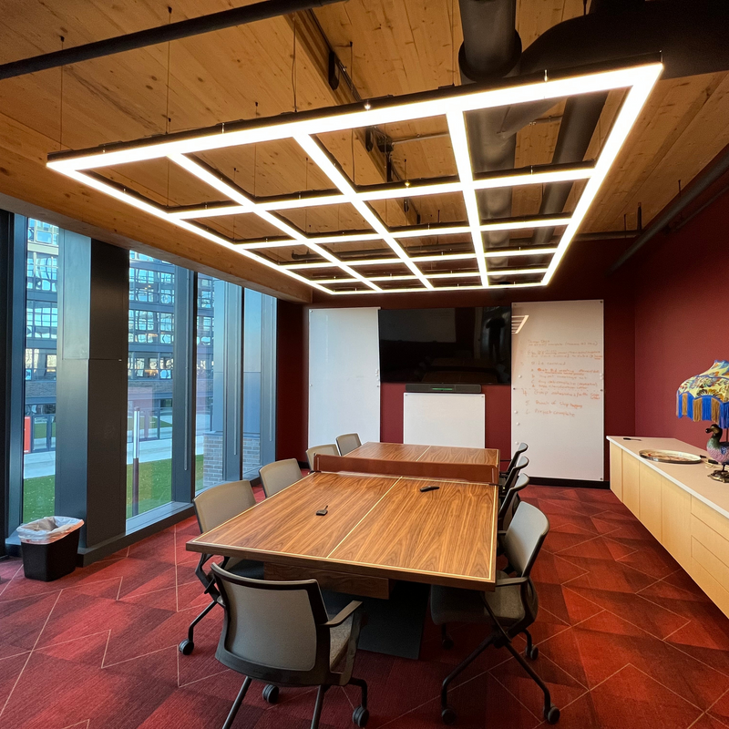 Modern office conference room with wooden table and chairs, large windows, and LED ceiling lights.