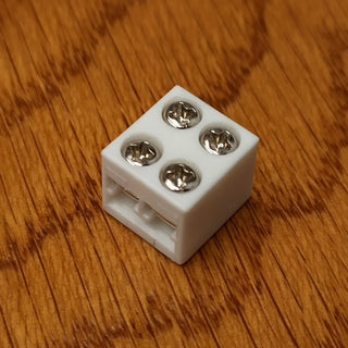A 2-Pin Solderless White LED Strip Screw Connector with four metal screw terminals sits on a wood grain surface.