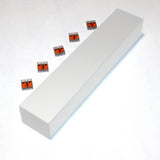 A Custom PL55 J-Box in white is on a light surface, surrounded by six small orange and gray plastic wire connectors used for electrical connections.