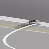A white, curved 0.39 Bendable Drywall LED Lighting Channel (Model Klus KOZEL-10-BD) shines on a gray surface, leading to a small wall opening accented by recessed lighting and a beige patterned strip in a minimal modern setting.