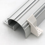 A plastic mounting bracket designed for the Caracas profile, shown in close-up with its detachable white end cap featuring two rows of base holes and curved grooves on a silver aluminum LED profile.