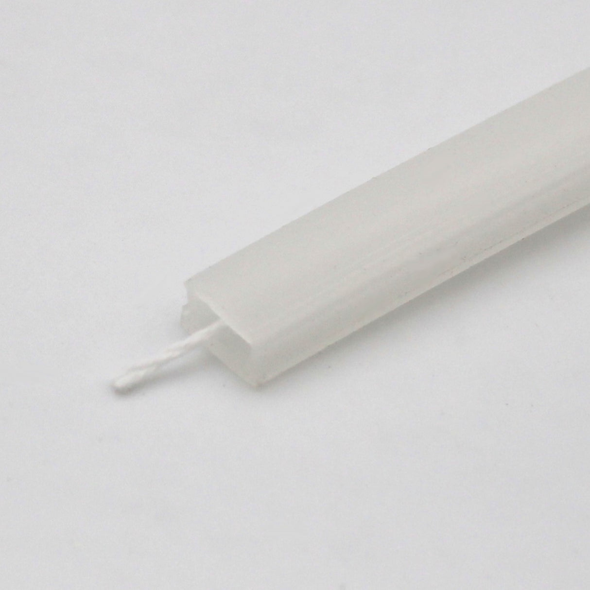 Close-up of a white candlewick inserted into the LED Channel Cover for KOZUS-BD Profile, a rectangular, translucent component shown on a plain white background.