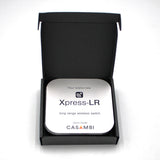 A black box opens to reveal a Casambi basicDIM Bluetooth LED Wall Remote Control ~ Model Xpress-LR Quick Guide, featuring simple icons and text for easy Casambi Bluetooth lighting control setup.