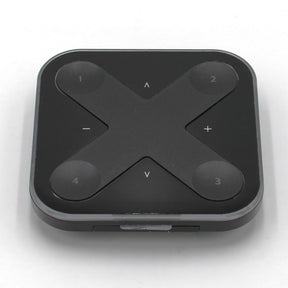The Casambi basicDIM Bluetooth LED Wall Remote Control (Model Xpress-LR) is a black, square remote with rounded corners and four numbered buttons at each corner, plus arrow and +/- symbols in an X pattern for wireless lighting control.