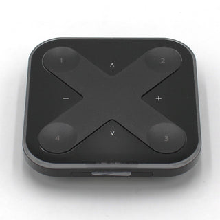 The Casambi basicDIM Bluetooth LED Wall Remote Control (Model Xpress-LR) is a black, square remote with rounded corners and four numbered buttons at each corner, plus arrow and +/- symbols in an X pattern for wireless lighting control.