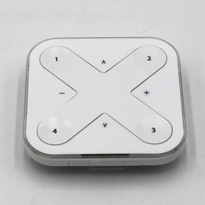 The Casambi basicDIM Bluetooth LED Wall Remote Control ~ Model Xpress-LR is a square, white remote with a large X-shaped button labeled 1-4 and plus/minus and up/down symbols, ideal for wireless lighting control via Casambi Bluetooth.