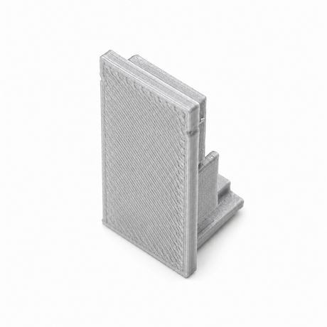 A small gray Plastic End Cap for Hannover Profile, 3D-printed and shaped like an open book, stands upright on a white background.