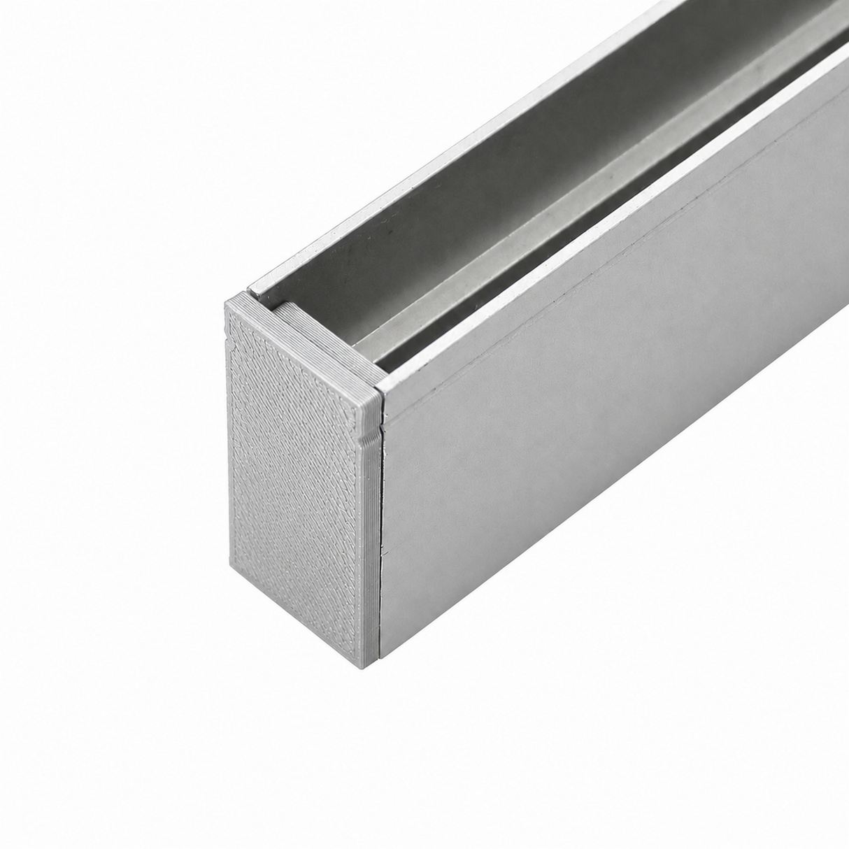 A close-up view of a rectangular metal channel with a hollow interior, featuring a Plastic End Cap for Hannover Profile, shown against a plain white background.