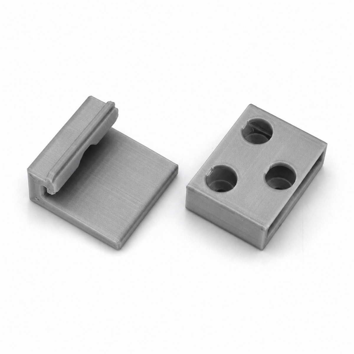 Two rectangular gray metal Wall Mounting Brackets for Hannover Profile—one with three circular holes, and the other with a flat base and a raised edge—are both placed on a white background.