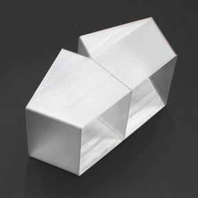 Two geometric, brushed silver Holston74 profile housings are joined side by side with a Translucent Elbow for Holston74 Profile, forming an abstract modern design against a black background.