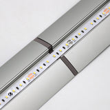 Close-up of a silver LED strip light on an Alu-Flat profile, featuring a seamless connection between two sections using the Plastic Straight Connector for Alu-Flat Profile. Small yellow and white LEDs are visible on the fixture.