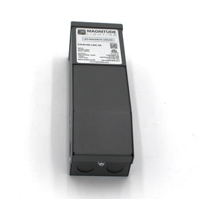 A rectangular black Magnitude M Series Dimmable Magnetic Core LED Driver (12V), showing model and certification labels, is viewed at a slight angle on a white background. It works with TRIAC dimmer controls for phase-dimmable lighting.