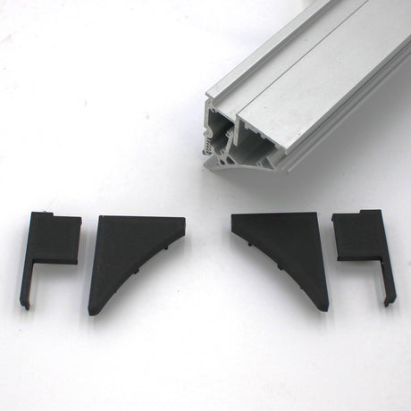 Shown on a white surface is a silver aluminum Pula P10 edge-lit shelf profile above four black plastic End Cap for Pula P10 Profile connectors.