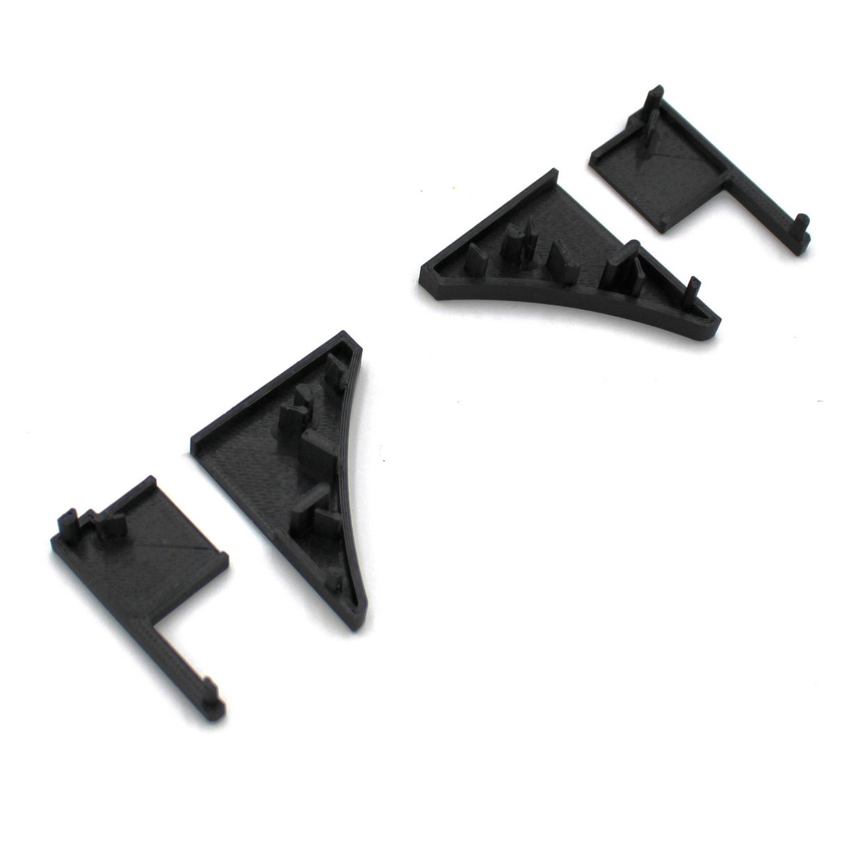 Four black End Caps for Pula P10 Profile are arranged on a white background, featuring small pegs and angled shapes—ideal components for assembling or joining structures with the Pula P10 edge-lit shelf profile.