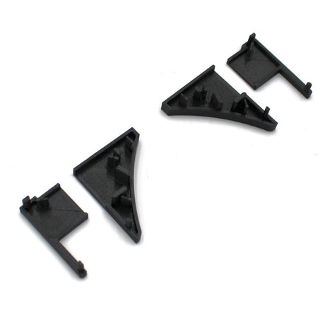 Four black End Caps for Pula P10 Profile are arranged on a white background, featuring small pegs and angled shapes—ideal components for assembling or joining structures with the Pula P10 edge-lit shelf profile.