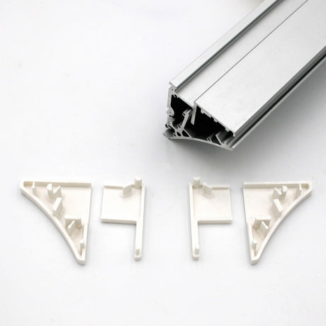 Four white End Caps for Pula P10 Profile are arranged below a Pula P10 edge-lit shelf profile rail with grooves, all displayed on a plain white background. The end caps are designed to fit and support the rail’s corners.