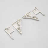 Three off-white PETG plastic End Caps for the Pula P10 Profile, featuring angular and rectangular shapes with raised pegs and flat bases, are arranged on a plain light gray background.