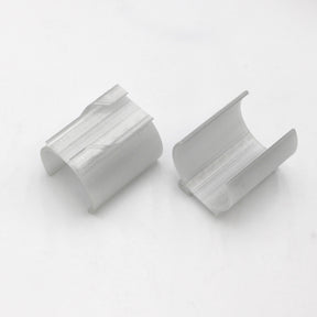 Two white Drop Ceiling T-Bar Clips for 1.5 round profiles, 3D printed with curved shapes, lie side by side on a white surface with their open sides facing outward—perfect for ceiling t-bar mounting.