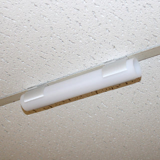 A close-up of a fluorescent light fixture mounted on a white, speckled drop ceiling tile using the Drop Ceiling T-Bar Clip for 1.5 Round Profiles for secure ceiling t-bar installation.