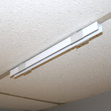 A Drop Ceiling T-Bar Linea20 Clip is installed in a white, textured ceiling with acoustic tiles and a drop-ceiling frame. The light fixture is currently turned off.