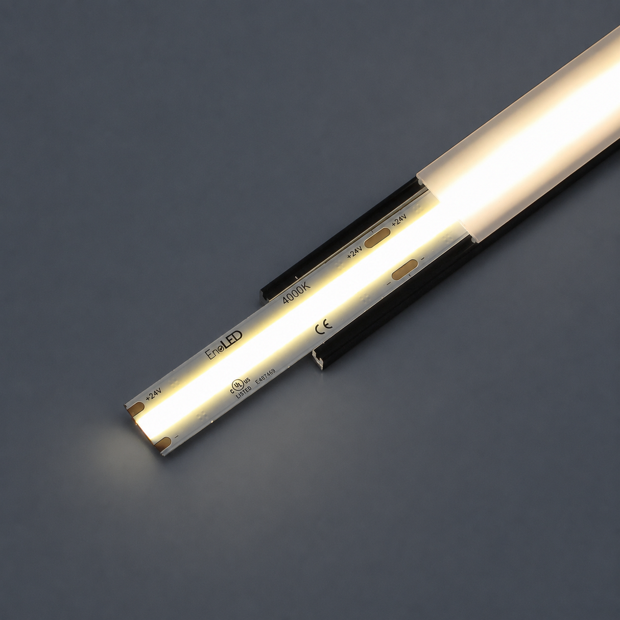 A UniBasic Series COB IP20 Dotless LED Strip (24V) is partially inserted into a black mounting track, emitting a warm white glow against a dark gray background.