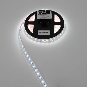 A reel of High CRI RGBW IP68 Waterproof LED Strip (24V) ~ Iris Series is partially unrolled on a white surface, shining brightly. The reel displays a label with text and the date 09/24/2024.