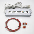 A Non-dimmable Plug-in LED Driver Kit (24V) ~ EnoLED ELD, with a silver driver, white power cord, coiled red-and-white wire, and three small orange wire connectors, is displayed on a white surface.