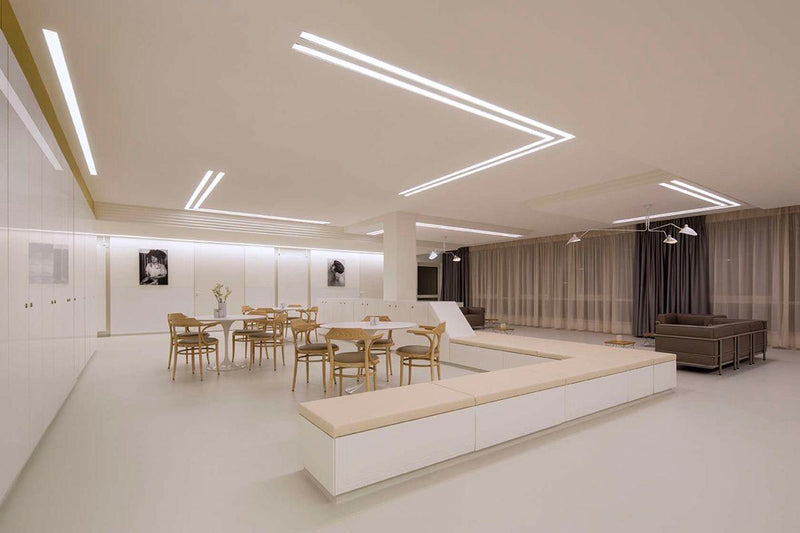 Large open-concept dining room and lounge lit with geometric patterns of cool white LED strip lights for a modern and uniform glow.