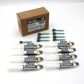 A brown box labeled “W4S M100” contains six 25ml 2-part Marine Methacrylate Adhesive syringes (1:1 B-System), each with a green mixing nozzle and black cap—ideal for high strength bonding applications.