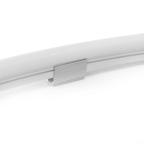 A close-up of a Neon-Style Flexible LED Light Line Max Series strip, curved and white or frosted, secured with a small rectangular aluminum Mounts For Neon-Style Flexible LED Light Line Max Series clip against a white background.