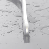A close-up of the Pixel IP44/IP66 Neon Flexible LED Light Line (24V) ~ Neon Flex Super Slim Pixel Series on a wet, reflective surface, showcasing its vibrant glow and dynamic possibilities for architectural lighting.