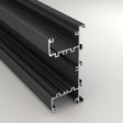 A close-up of the Up & Down Wall Feature Lighting LED Profile ~ Model New Washington, a black aluminum extrusion with multiple grooves, designed for LED accent installation in architectural projects, shown against a light gray background.