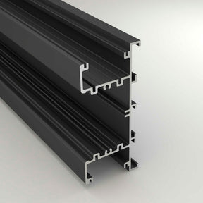 A close-up of the Up & Down Wall Feature Lighting LED Profile ~ Model New Washington, a black aluminum extrusion with multiple grooves, designed for LED accent installation in architectural projects, shown against a light gray background.