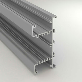 A 3D render of the Up & Down Wall Feature Lighting LED Profile ~ Model New Washington, a gray aluminum extrusion with multiple grooves for modular framing or LED strip accent lighting, is displayed on a light background.