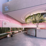 Modern cafe interior with pink herringbone walls, green velvet booth seating, and a round bar. Curved 0.8 Bendable Drywall LED Lighting Channel (Model Klus KOZMA-BD) highlights the greenery and neon sign for a bright, airy ambiance.