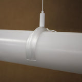 A translucent Mounting Clip for 2.56" Round Profiles secures a white cylindrical rod, with a thin white cord attached to the clip, all set against a plain brown background.