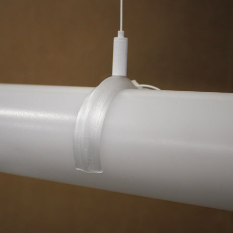 A translucent Mounting Clip for 2.56" Round Profiles secures a white cylindrical rod, with a thin white cord attached to the clip, all set against a plain brown background.