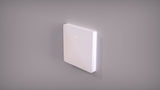 The Casambi Wireless Battery-Operated Single-Button Wall Switch (Eulum SWC-CSB-1R-W) is a white, rectangular switch with smooth edges and a yellow indicator, mounted on a gray wall. It enables wireless lighting control via the Casambi app.