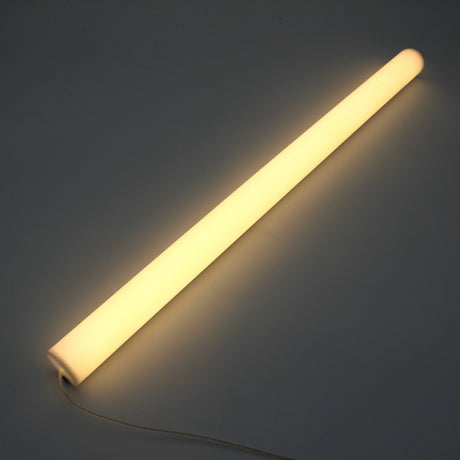 The 1.5" White Surface-mount LED Tube Lighting Fixture (24V) from the Sierra38 Series glows warmly on a dark surface with its power cord visible—perfect for easy, plug-and-play surface mounting.