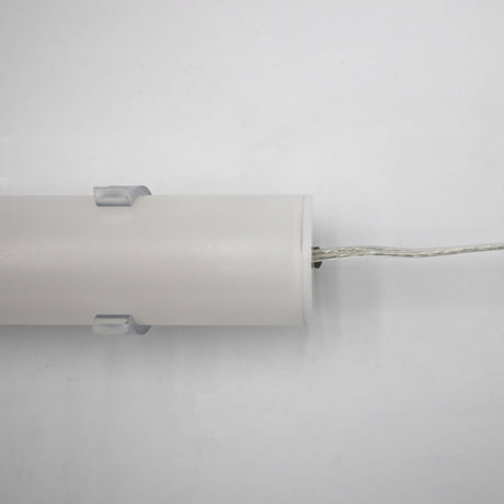 The 1.5" White Surface-mount LED Tube Lighting Fixture (24V) ~ Sierra38 Series rests on a white surface, featuring two clear mounting clips and a thin silver wire extending from one end, showcasing its convenient plug-and-play design.