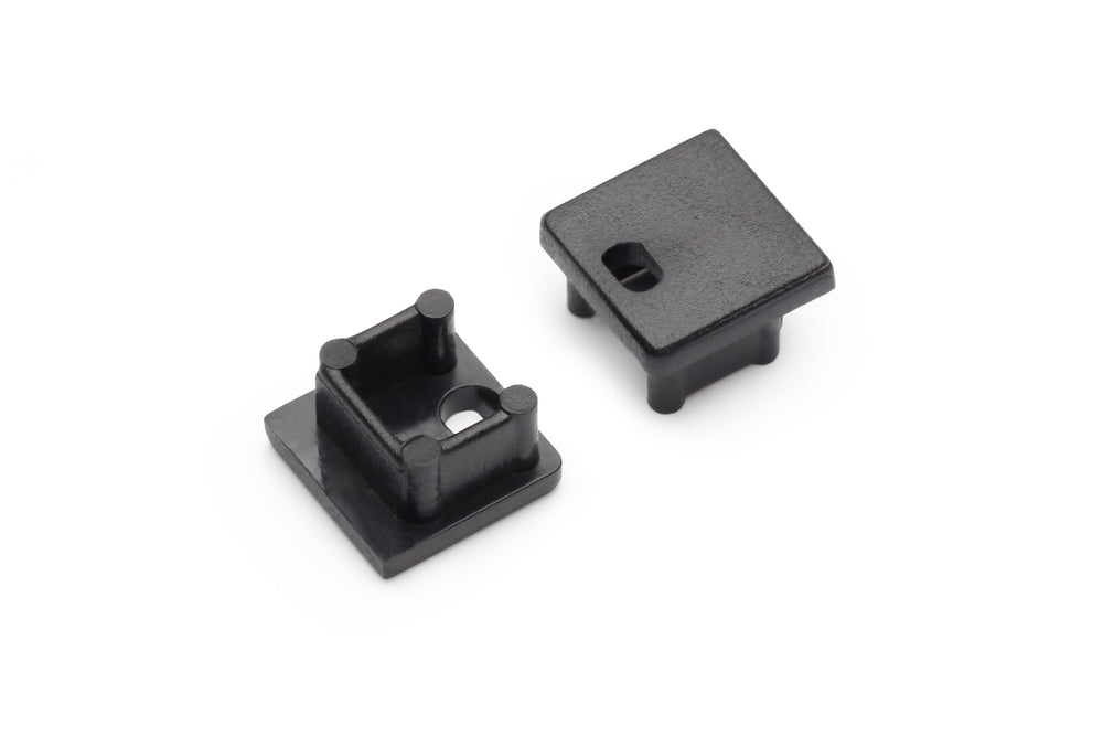 Two small black plastic End Caps for Smart10 Profile are shown: one upright with two pegs and a central hole, the other flat, revealing a rectangular top with a hole. Both are ideal for use with Smart10 profile lighting fixtures.