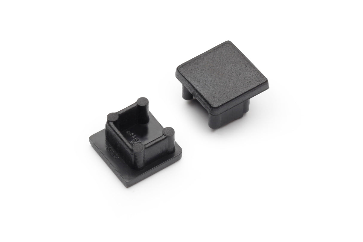 Two black End Caps for Smart10 Profile are displayed on a white background—one upright showing its smooth exterior, the other flipped to reveal four interior support pegs. Both are made of plastic and designed to fit the Smart10 lighting fixture.