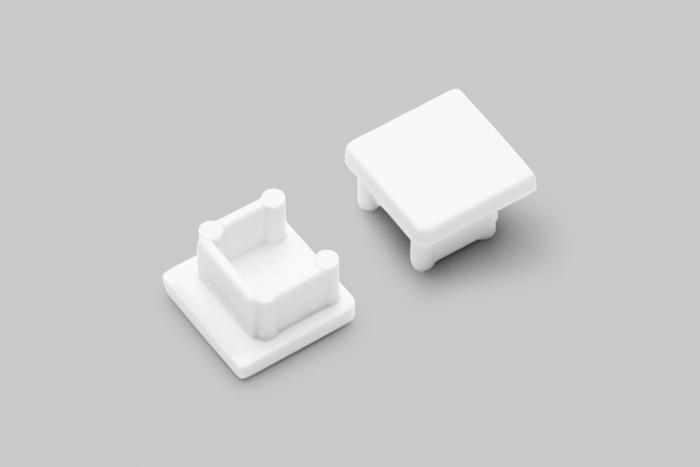 Two white plastic End Caps for the Smart10 Profile, each with short posts underneath, are shown on a light gray background. One cap is upside down to display its internal design, suitable for use with the Smart10 profile lighting fixture.