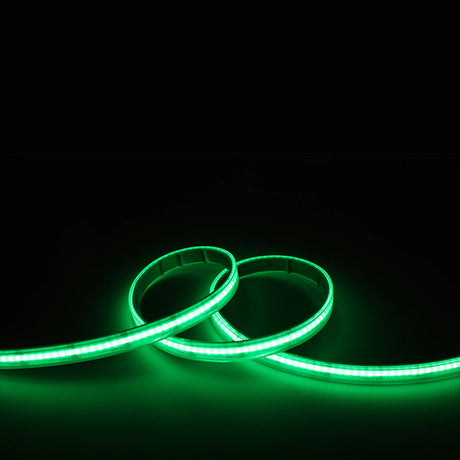 Two flexible EnoLED UniColor Series RGB+CCT COB IP67 High CRI LED Strips (24V) form loose loops, emitting a vivid green glow against a solid black background.