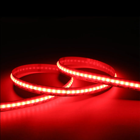 A close-up of the EnoLED UniColor Series RGB+CCT COB IP20 High CRI LED Strip (24V) glowing bright red, coiled loosely on a flat surface against a dark background.