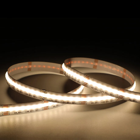 A close-up of two loops of EnoLED UniColor Series RGB+CCT COB IP20 High CRI LED Strip (24V) glowing on a dark surface, illuminating their surroundings with soft, even light.