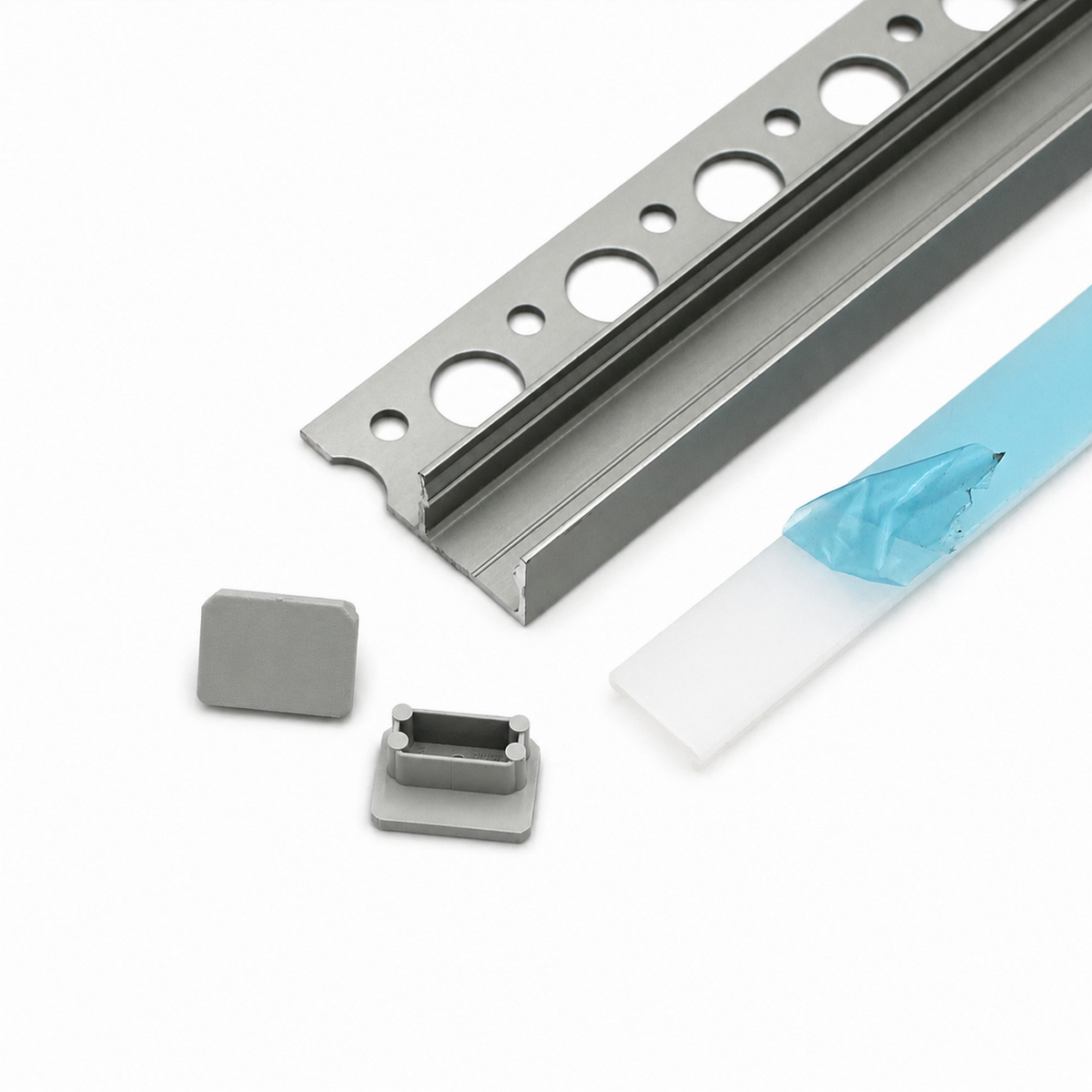 The Uni-Tile12 180Deg Tile Edge LED Strip Light Channel Kit features a metal trim strip with round holes and a groove, two rectangular gray plastic end caps, and a blue-and-white protective film, all displayed on a white background.