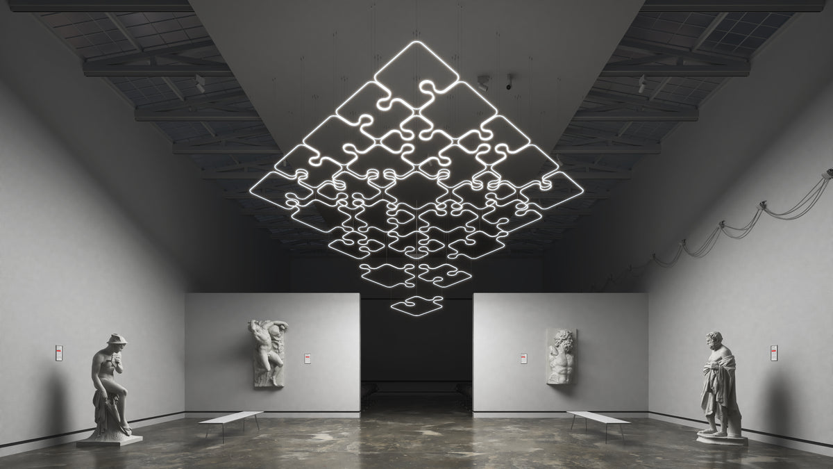 A large, puzzle-shaped 0.51″ Suspended/Surface Mount Bendable LED Channel ~ Model Bend8 fixture suspended from the ceiling in a gallery space containing classical statues.