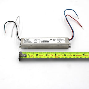 A Slimline Small Constant Voltage LED Driver (12V) ~ ERP Power VLM Series with black, white, red, and blue wires rests on a white surface above a yellow measuring tape, showing its IP20-rated body is about 7 inches long.