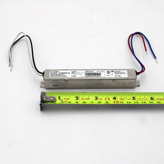 A Slimline Small Constant Voltage LED Driver (24V) from the ERP Power VLM Series, with wires at both ends, is placed above a yellow measuring tape showing its length of about 6 inches (15 cm); specs and constant voltage are shown on its label.